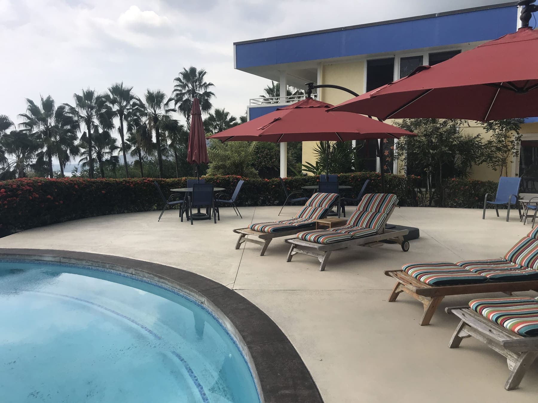 Large stained pool deck with loungers and red umbrellas